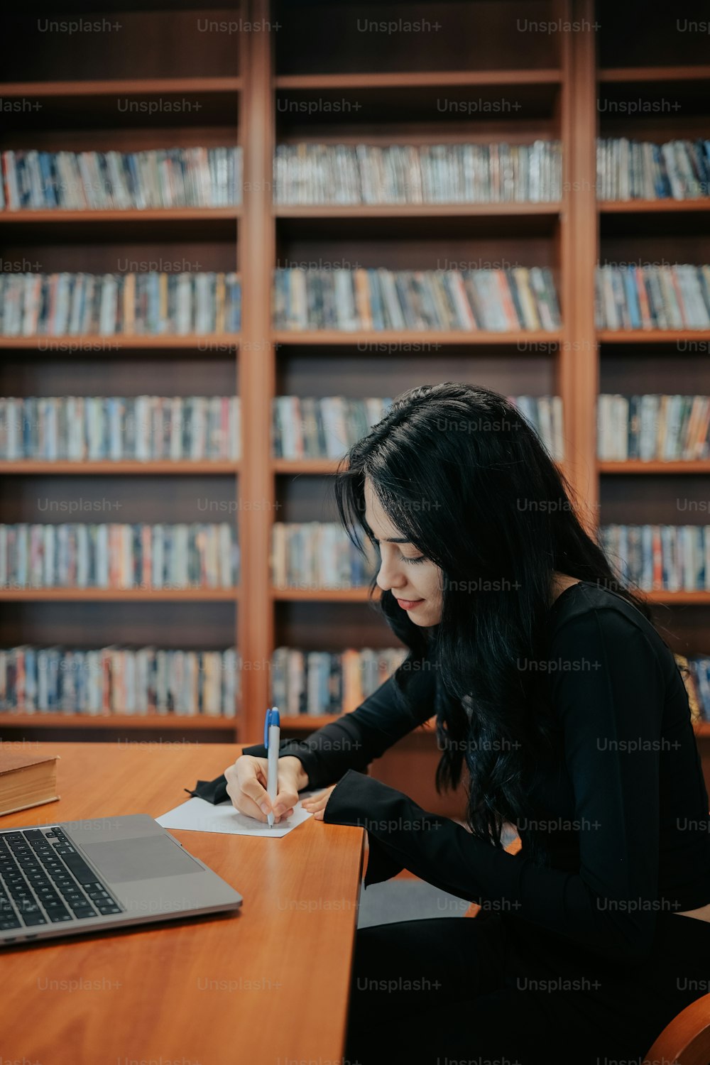 a woman sitting at a desk writing on a notebook