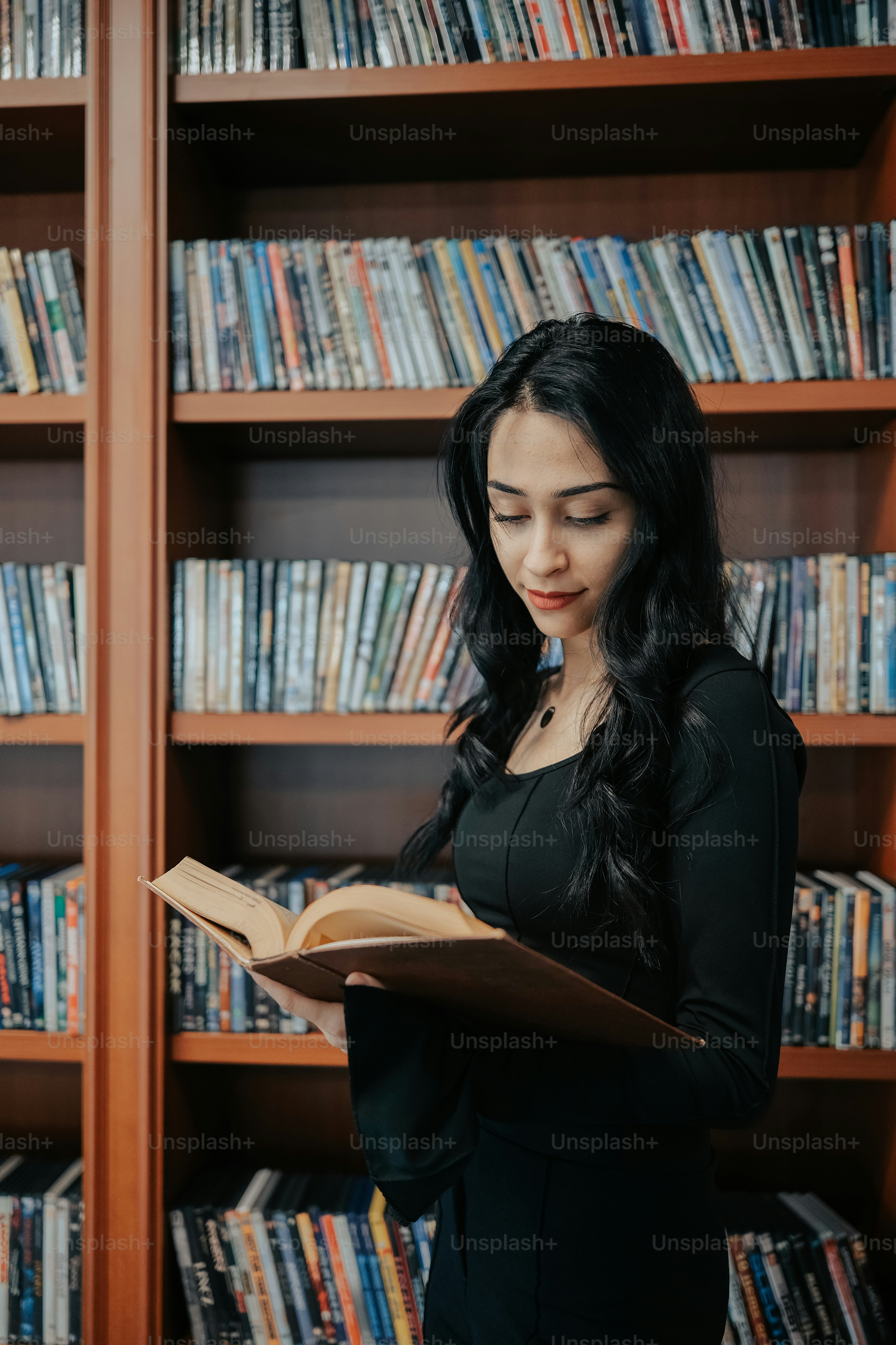 a woman reading a book in front of a bookshelf
