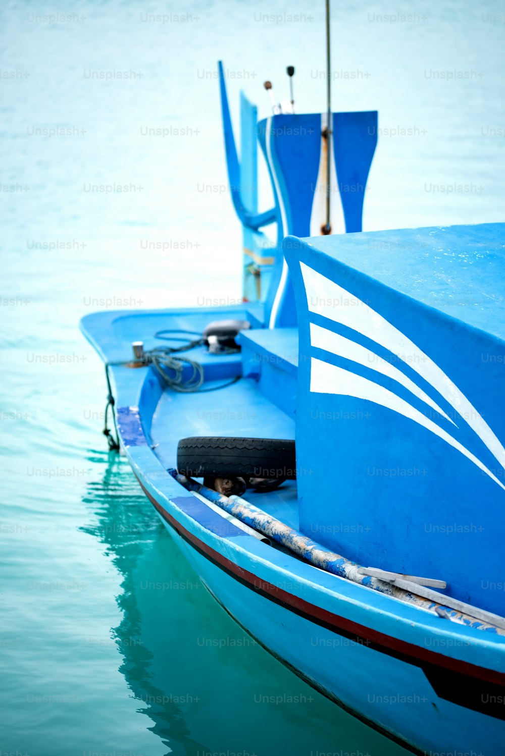 um pequeno barco azul flutuando em cima de um corpo de água