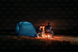 Eine Gruppe von Menschen, die um ein Lagerfeuer sitzen