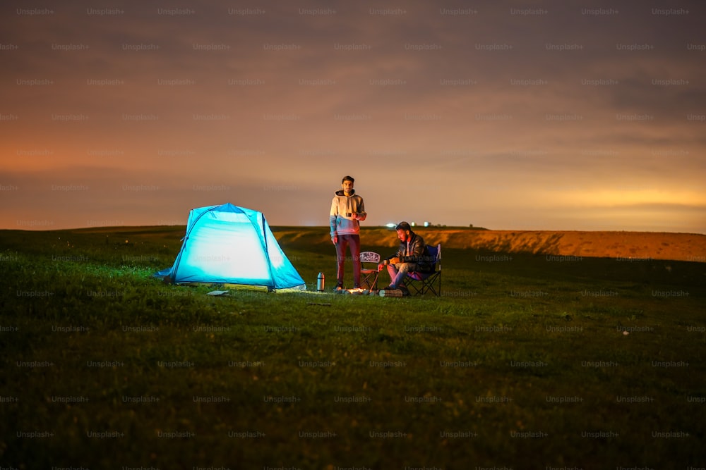 Un couple de personnes debout à côté d’une tente bleue