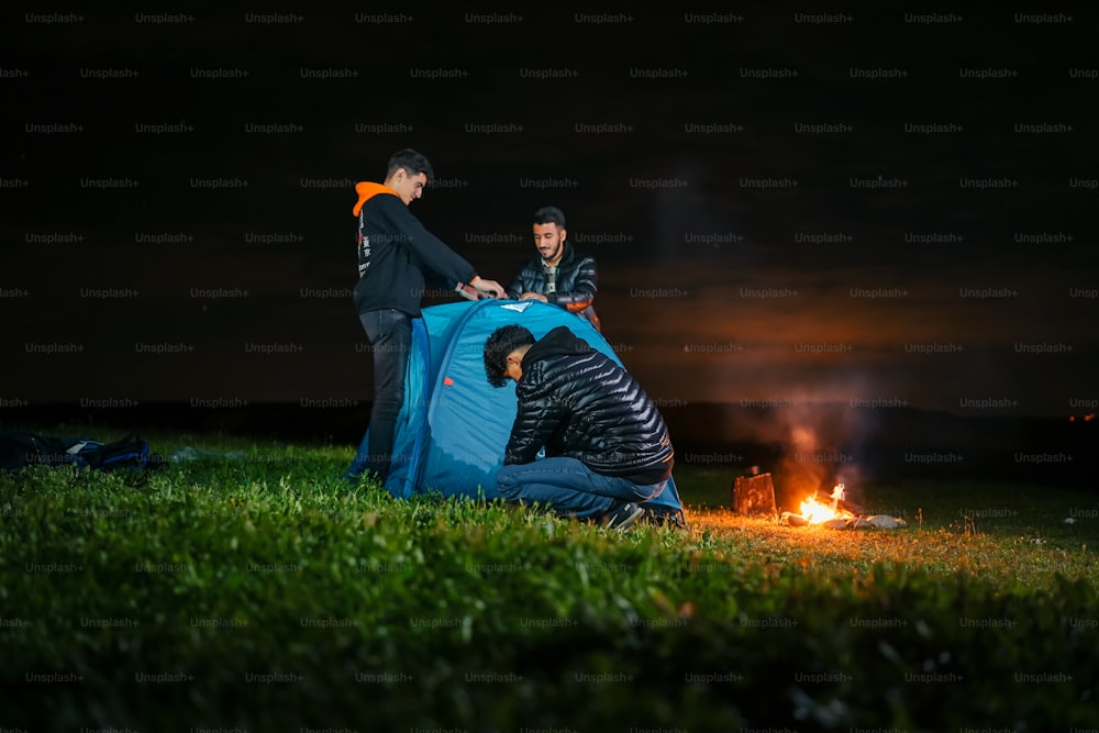 Un couple d’hommes debout à côté d’une tente bleue