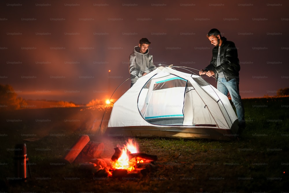 um casal de homens ao lado de uma tenda