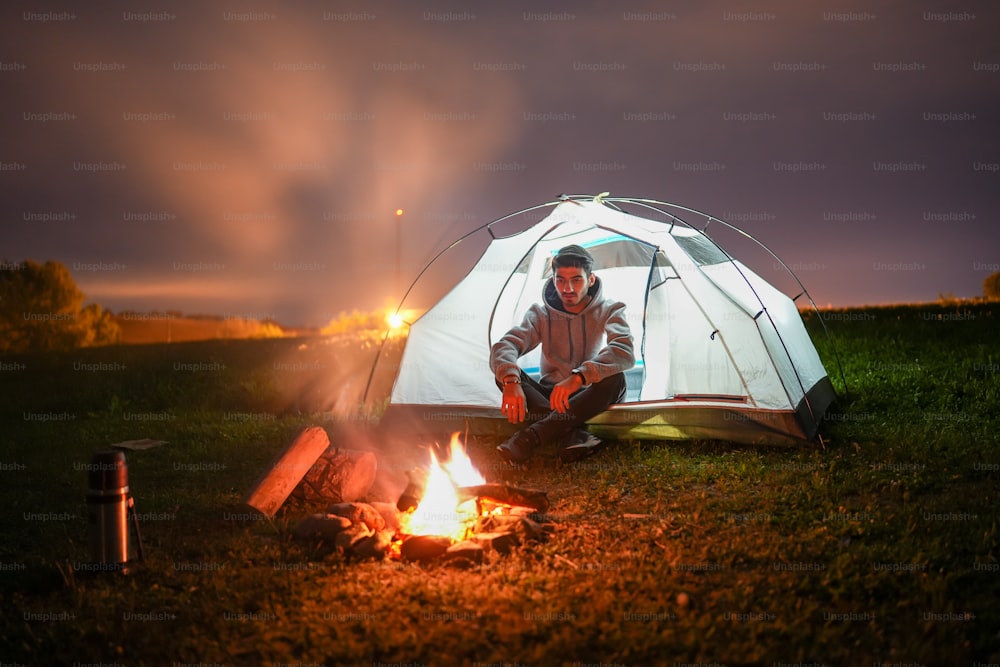 a man sitting in front of a campfire at night