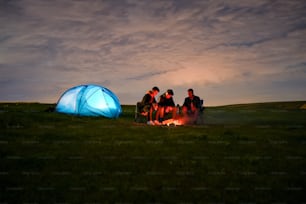 a group of people sitting around a campfire