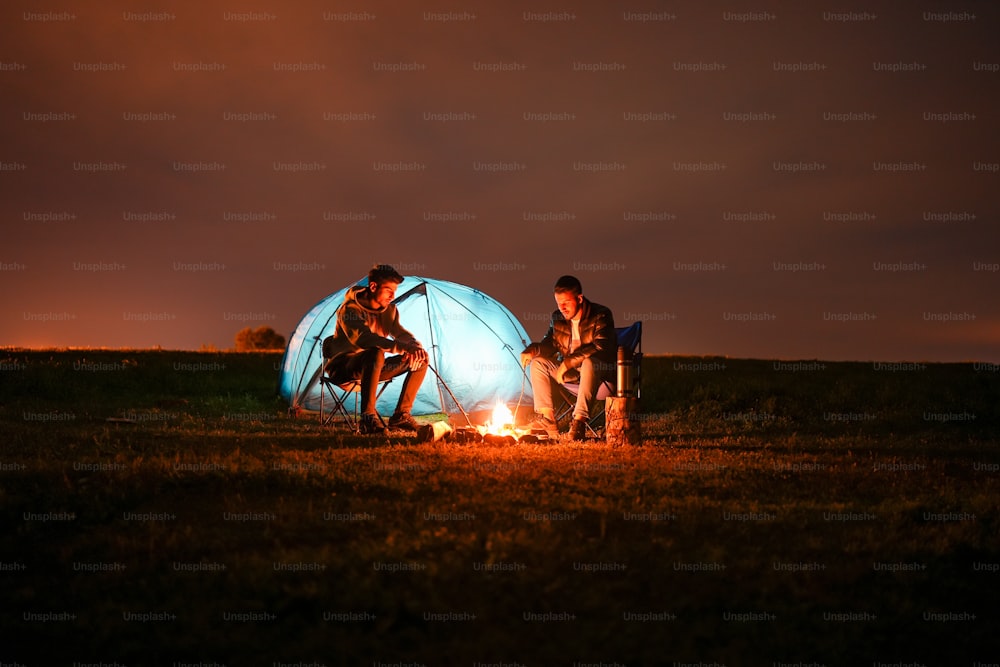 Drei Personen sitzen nachts um ein Lagerfeuer
