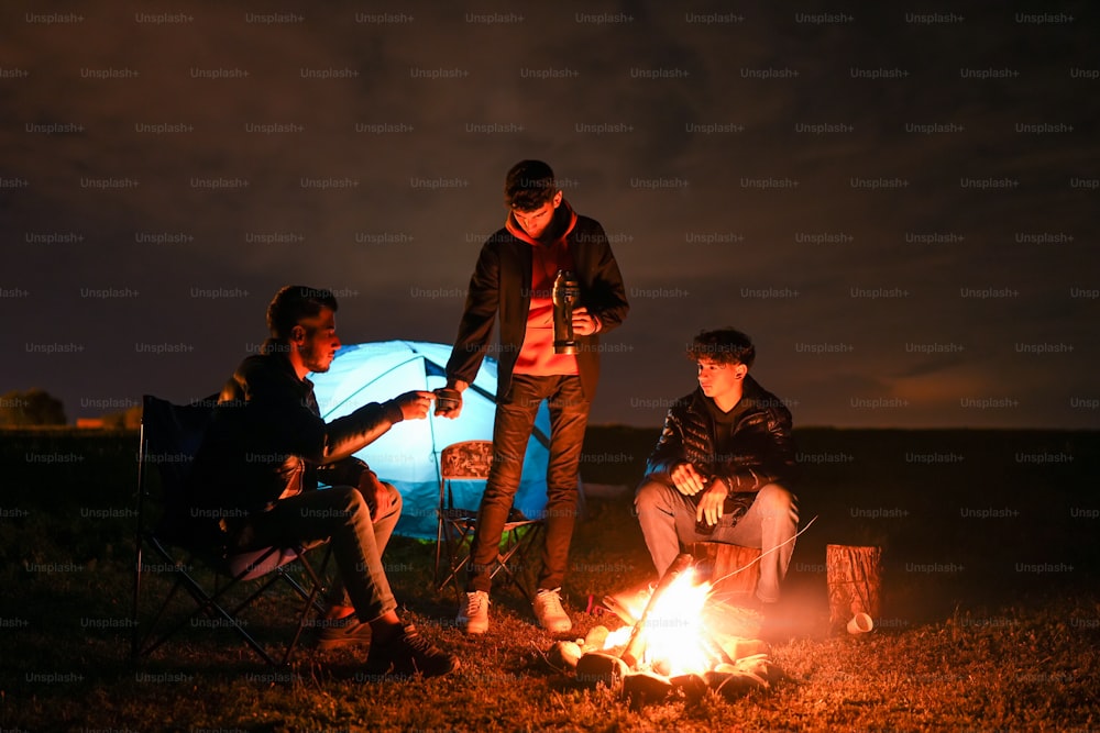 un groupe de personnes assises autour d’un feu de camp