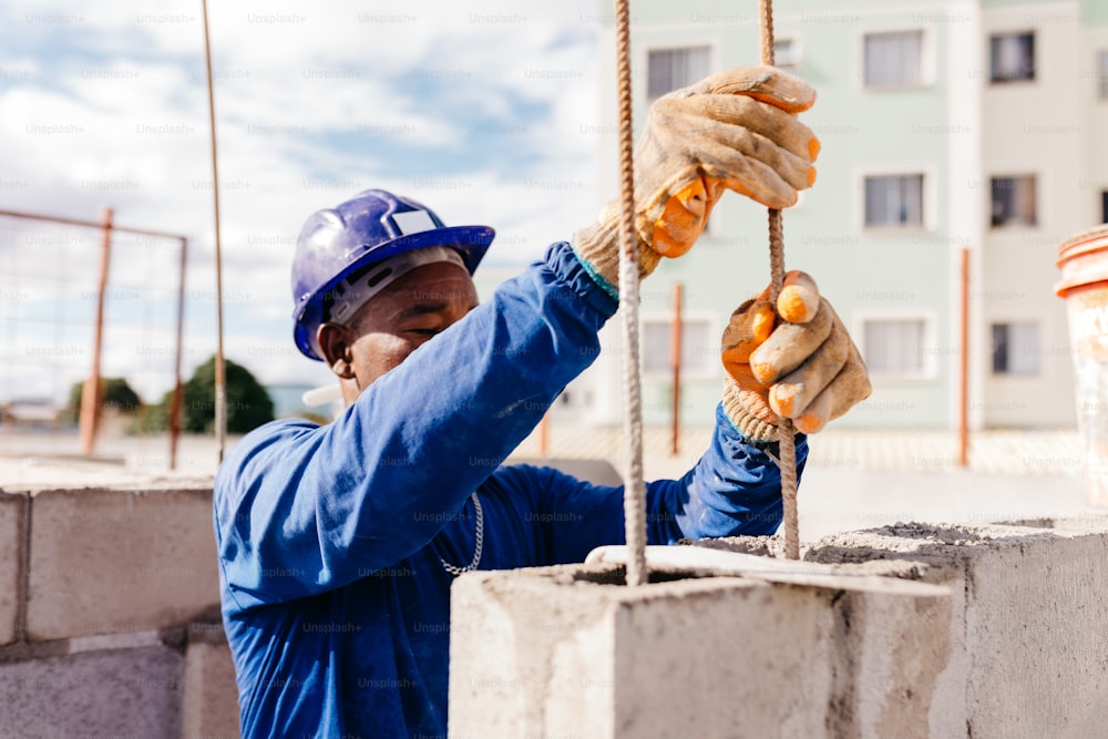 a man in a hard hat and blue jacket holding a rope