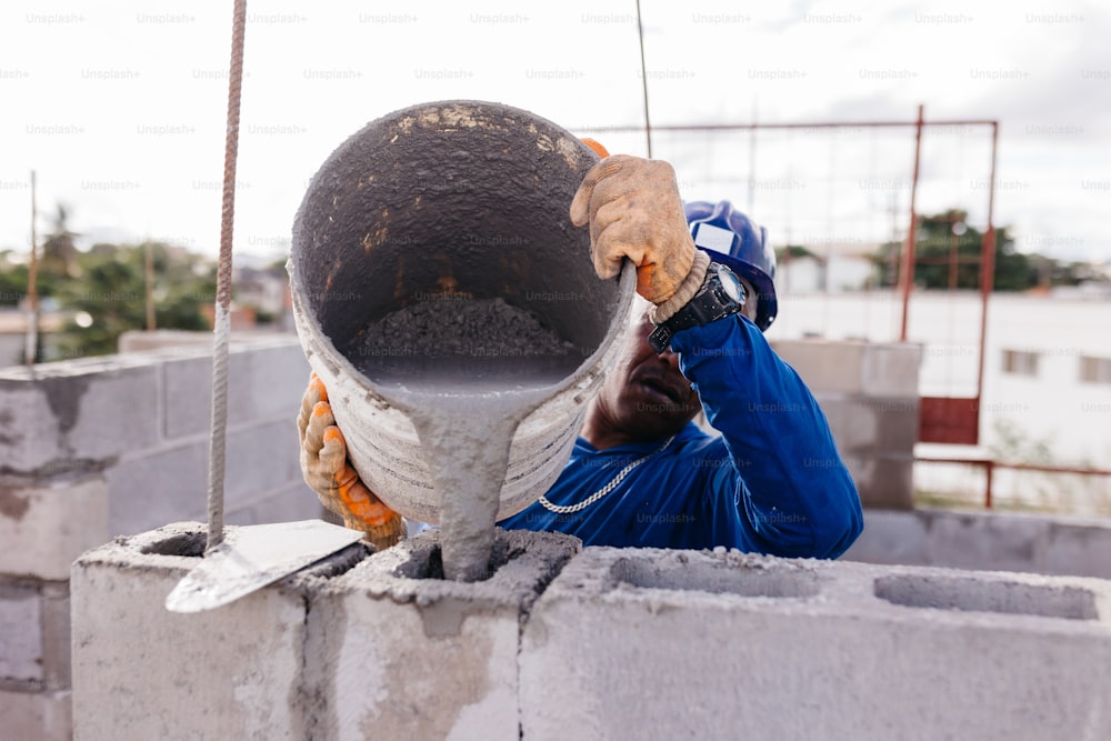 a man in blue overalls and safety gear working on a pipe