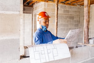 a man in a hard hat is looking at a piece of paper