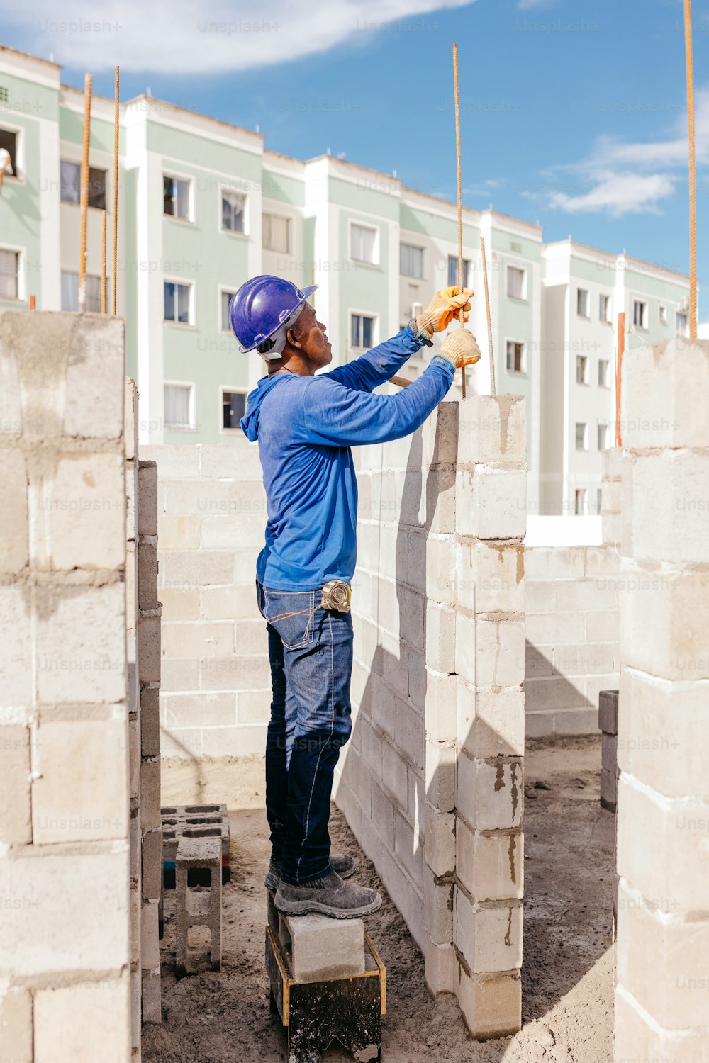 a man in blue shirt and helmet working on a building