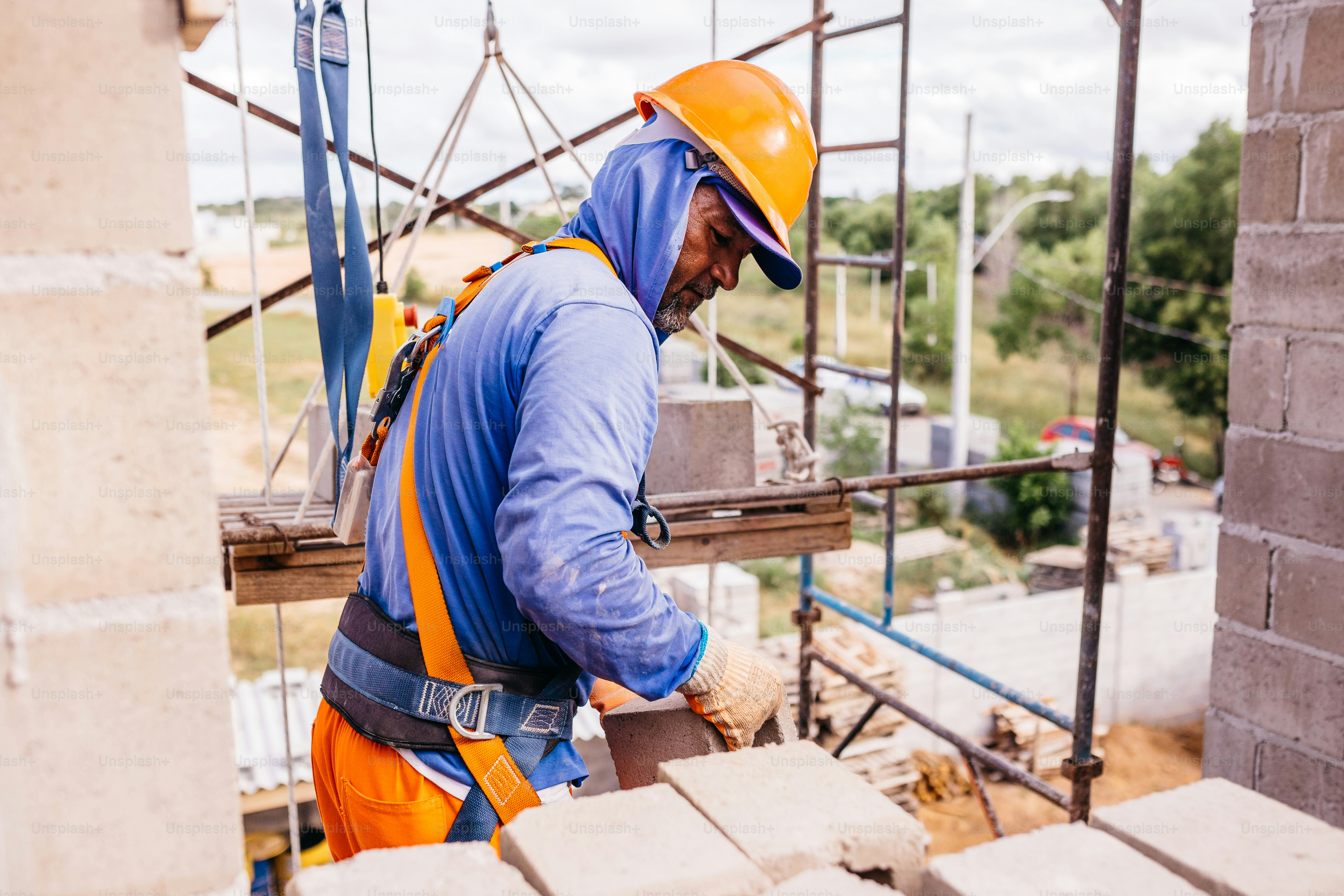 Two men in orange and blue work on a construction site photo – Building ...