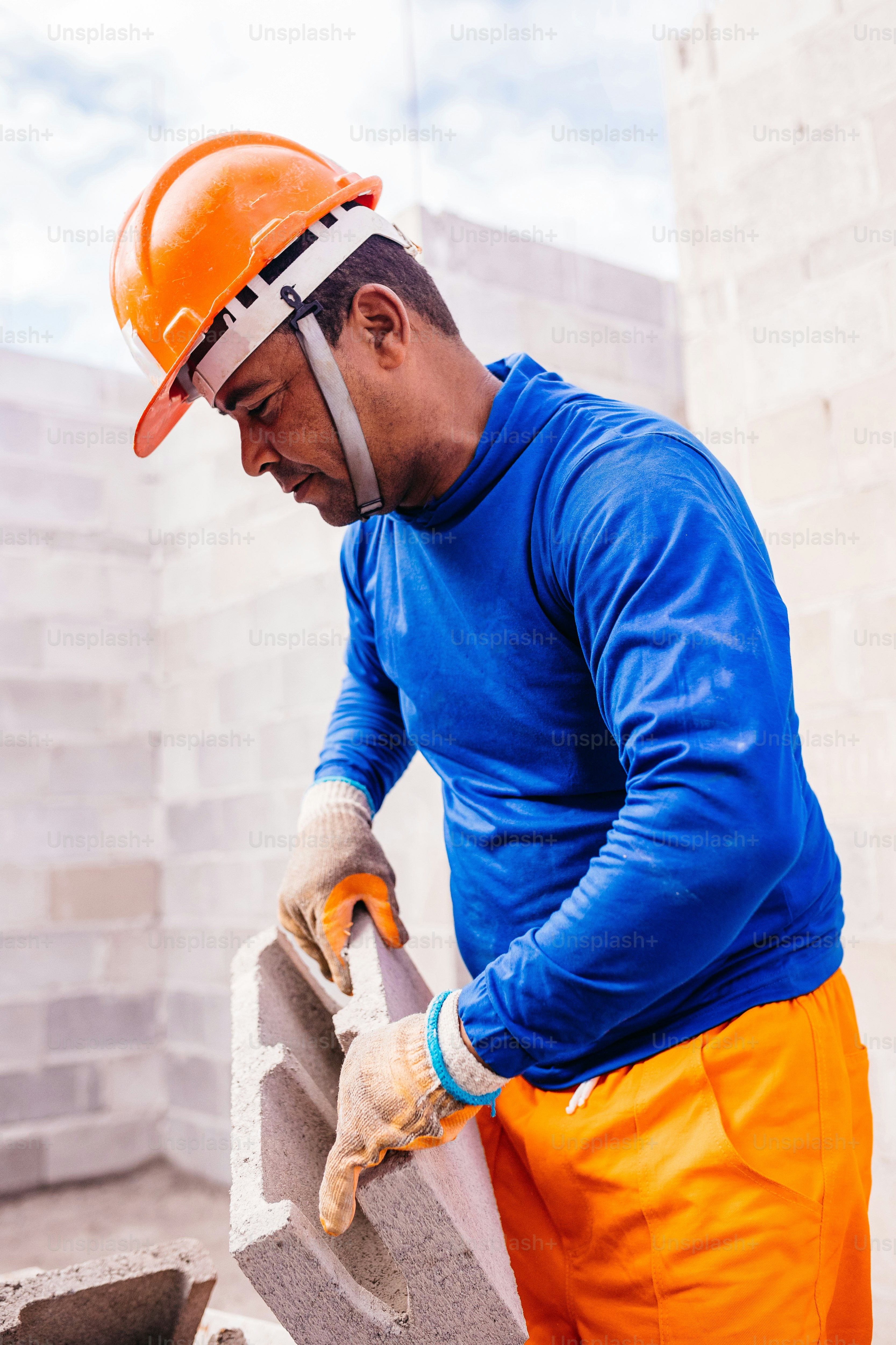 a man wearing a hard hat and orange pants