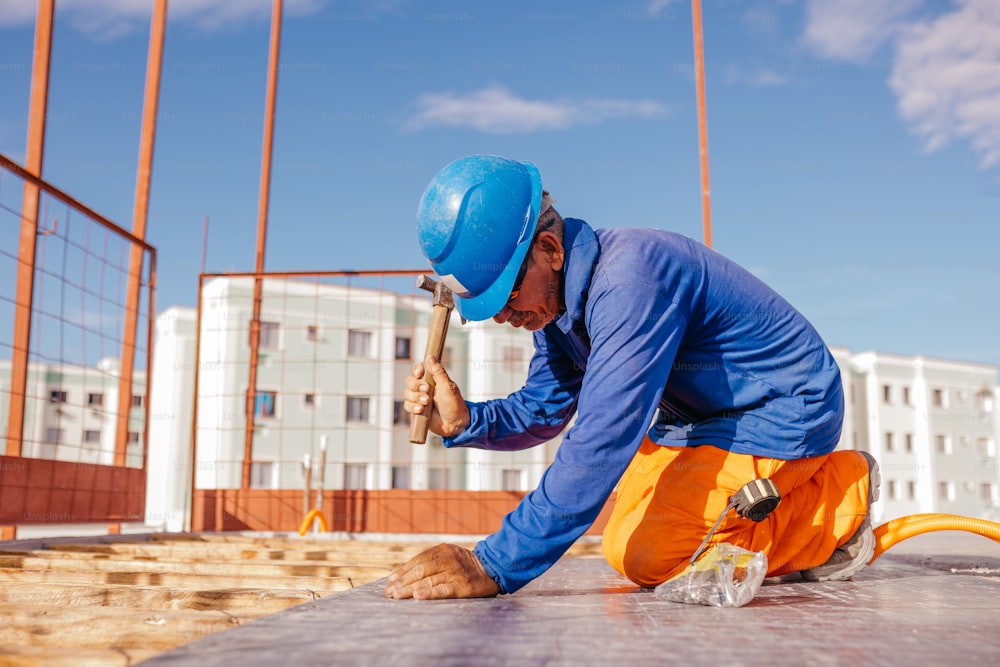 a man in a hard hat and overalls working on a construction site