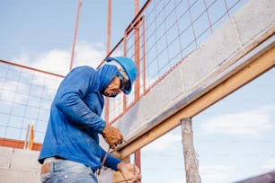 a man in a blue hoodie working on a fence
