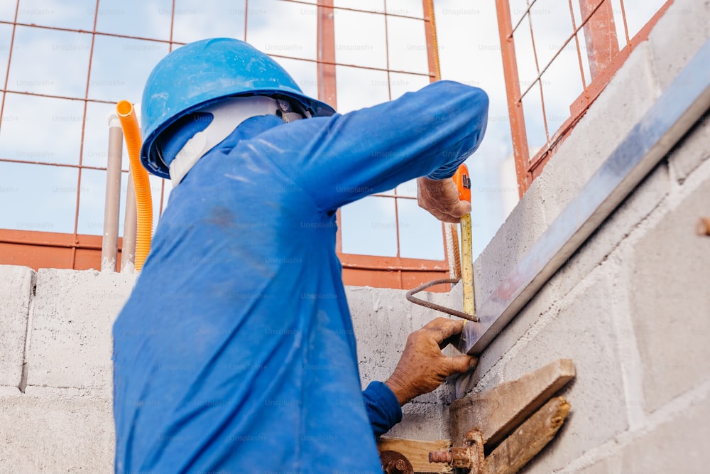 a man in a blue coverall working on a wall