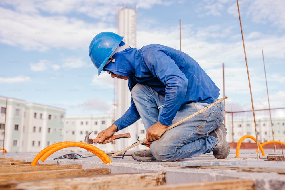 a man in a blue shirt and helmet working on a piece of wood