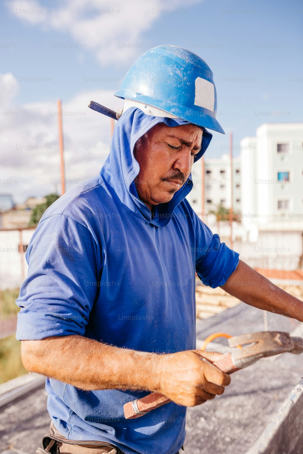 a man in a blue shirt and a hard hat working on a roof
