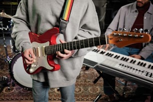 a man holding a red guitar in front of a keyboard