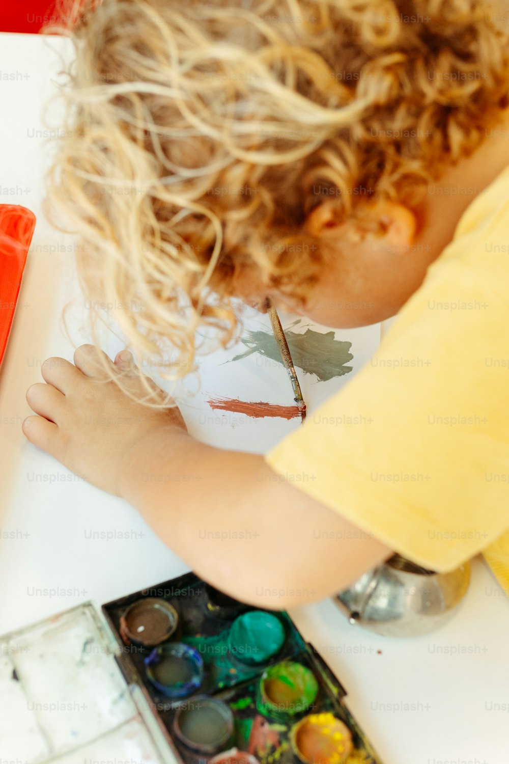 a young boy is painting a picture on a table