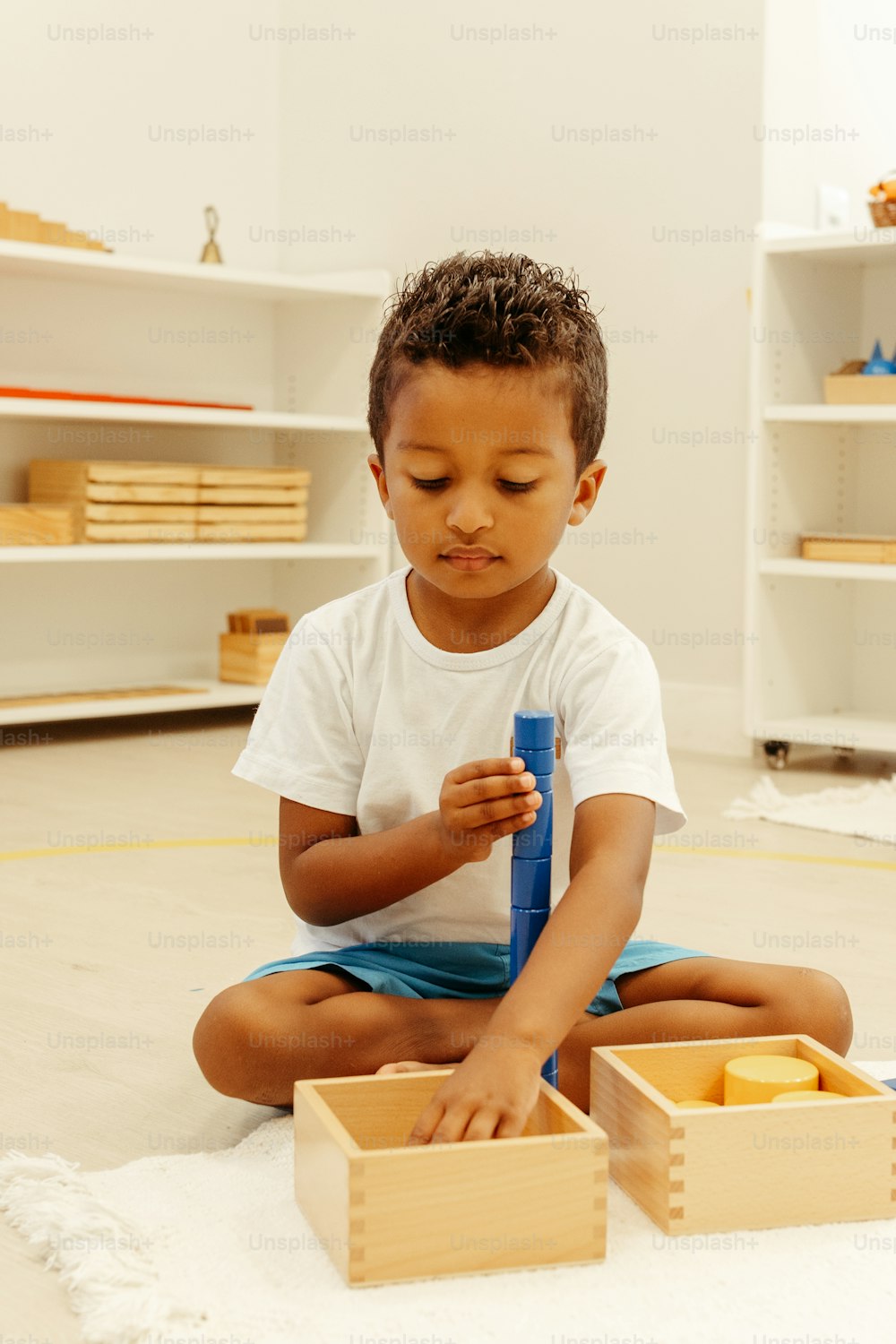 a little boy sitting on the floor playing with a blue toothbrush