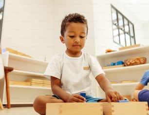 a young boy sitting on the floor playing with wooden blocks