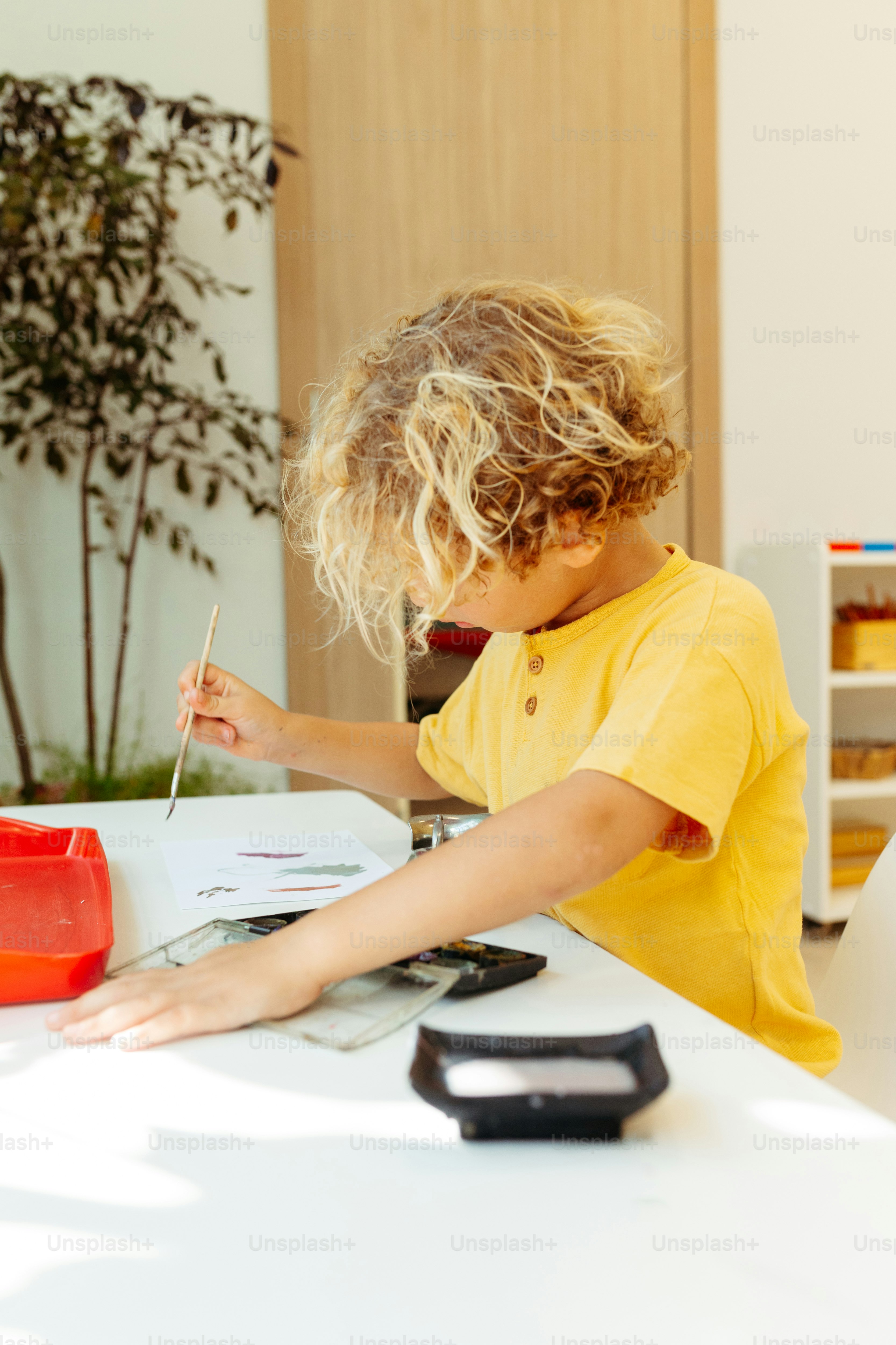 a little boy sitting at a table writing on a piece of paper