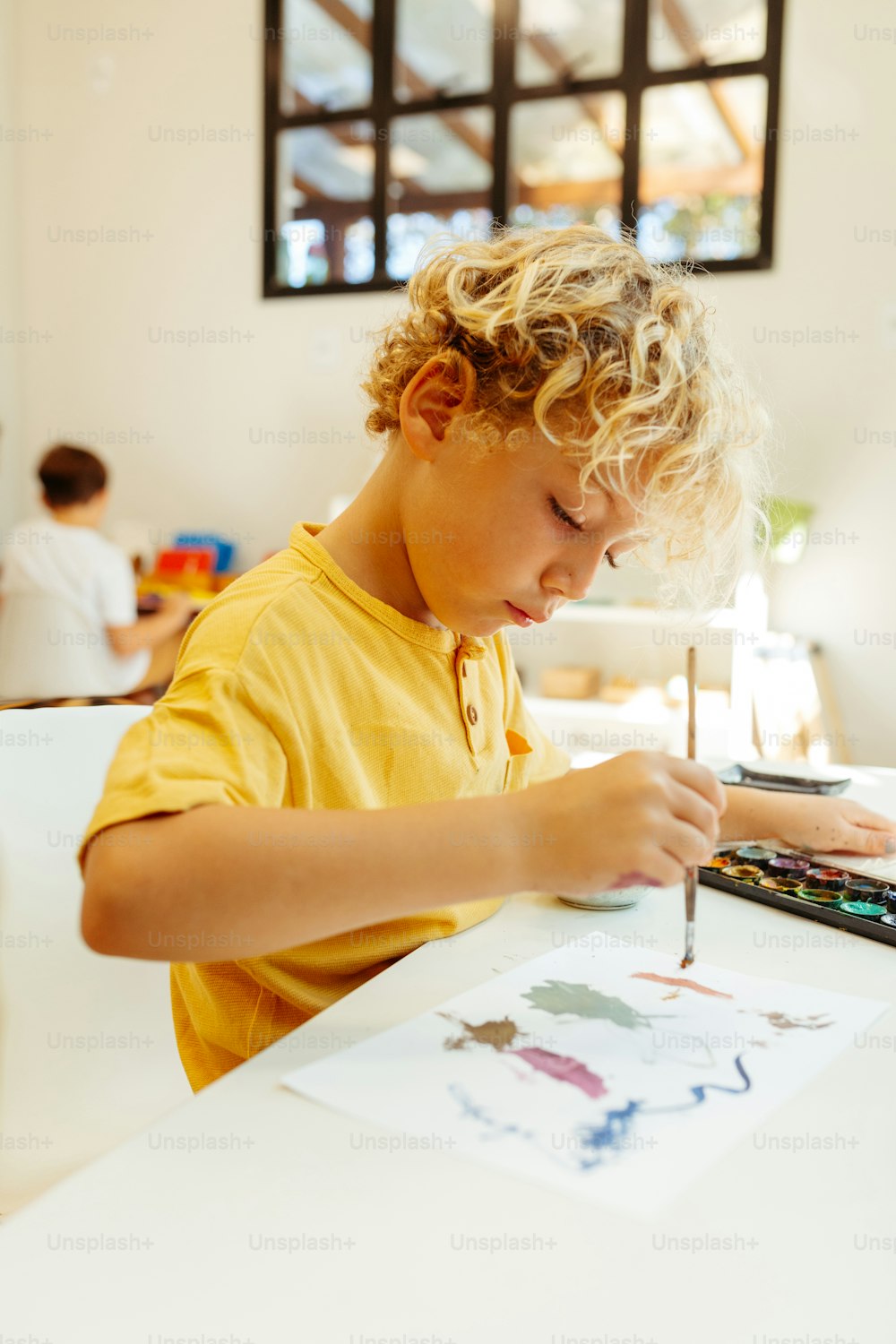 Un jeune garçon assis à une table avec un crayon et du papier