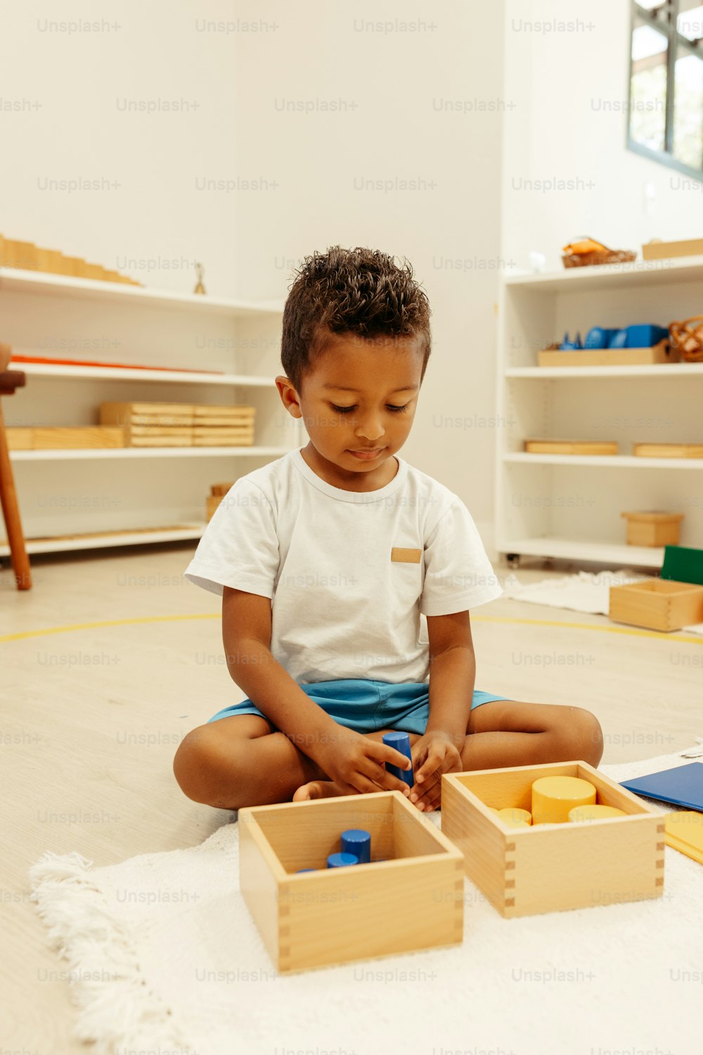 un ragazzino seduto sul pavimento che gioca con blocchi di legno