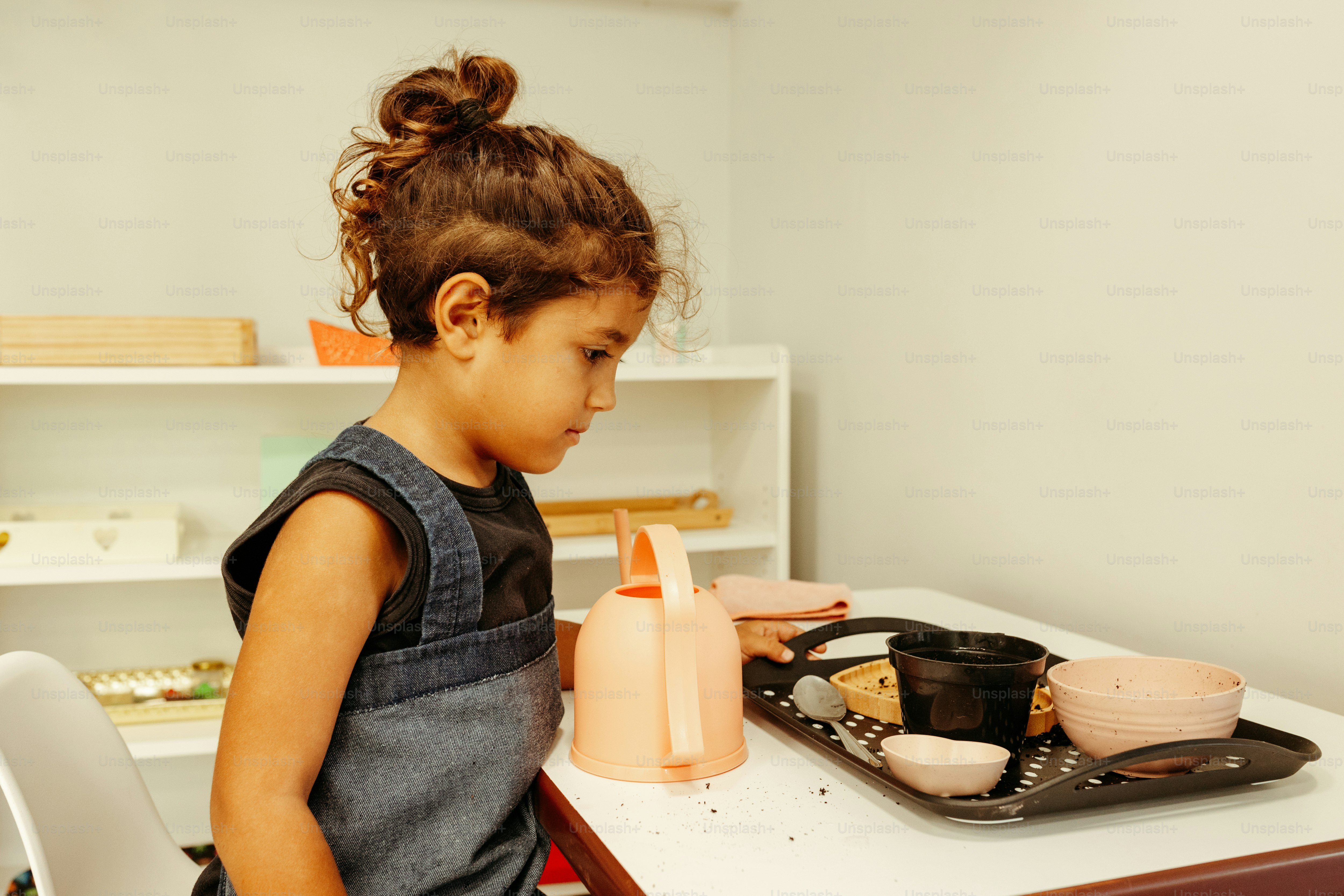 a little girl sitting at a table with a plate of food