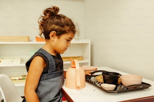 Una niña sentada en una mesa con un plato de comida