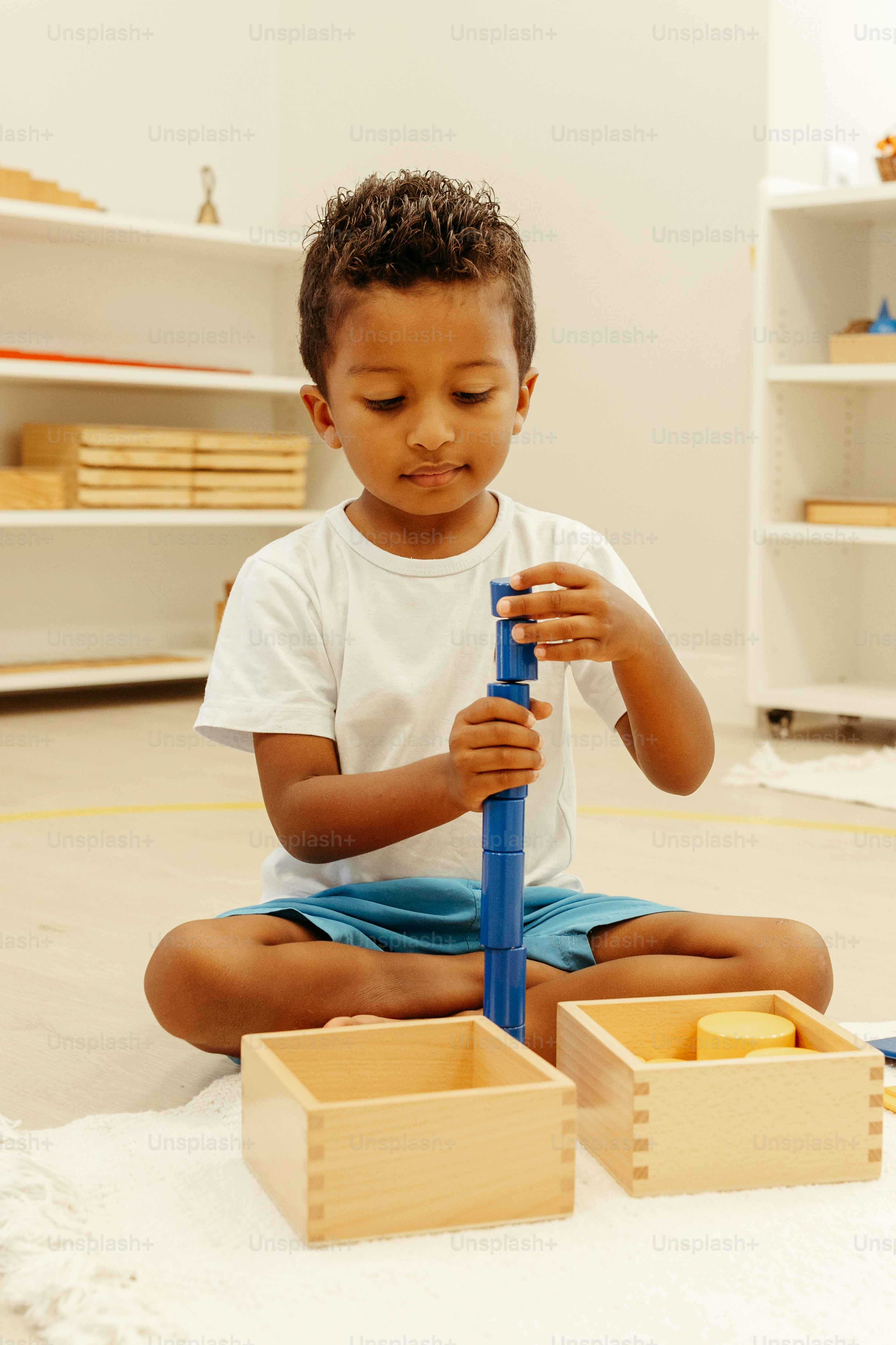 a little boy sitting on the floor playing with a blue umbrella