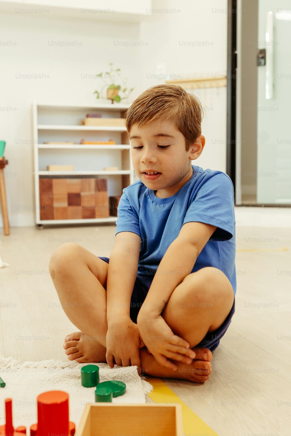 장난감을 가지고 노는 바닥에 앉아 있는 어린 소년