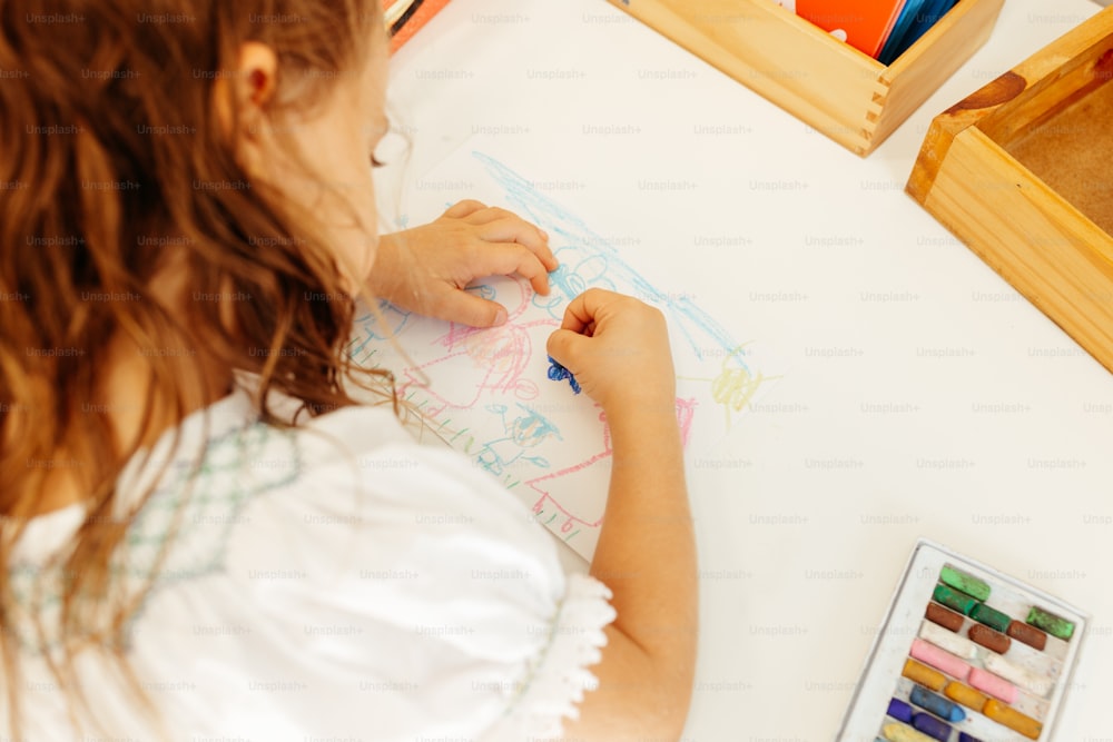 Ein kleines Mädchen zeichnet auf einem Blatt Papier