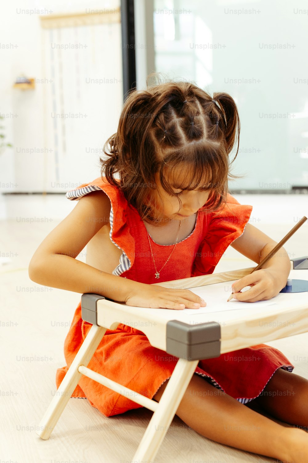 Una niña sentada en el suelo escribiendo en un pedazo de papel