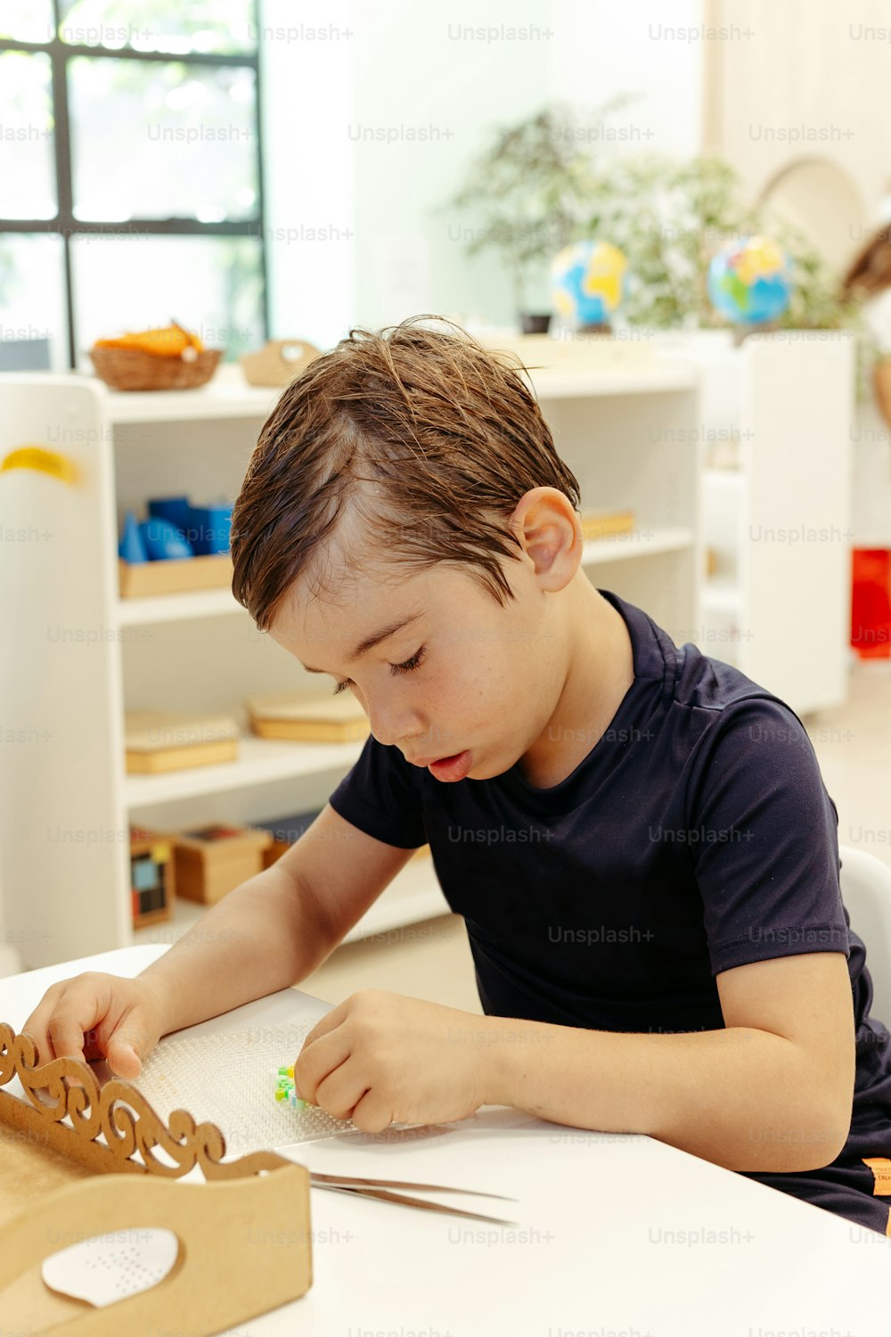 a young boy sitting at a table working on a project
