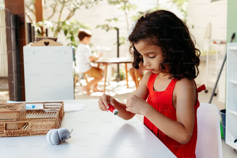 a little girl in a red dress playing with a cell phone