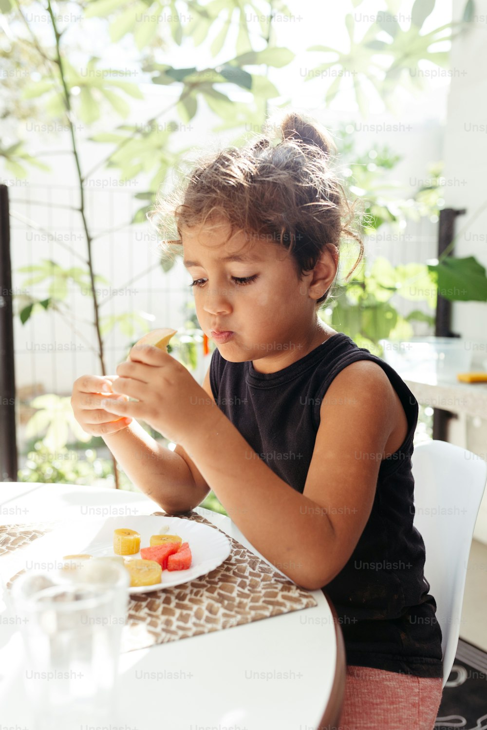 a little girl sitting at a table eating food
