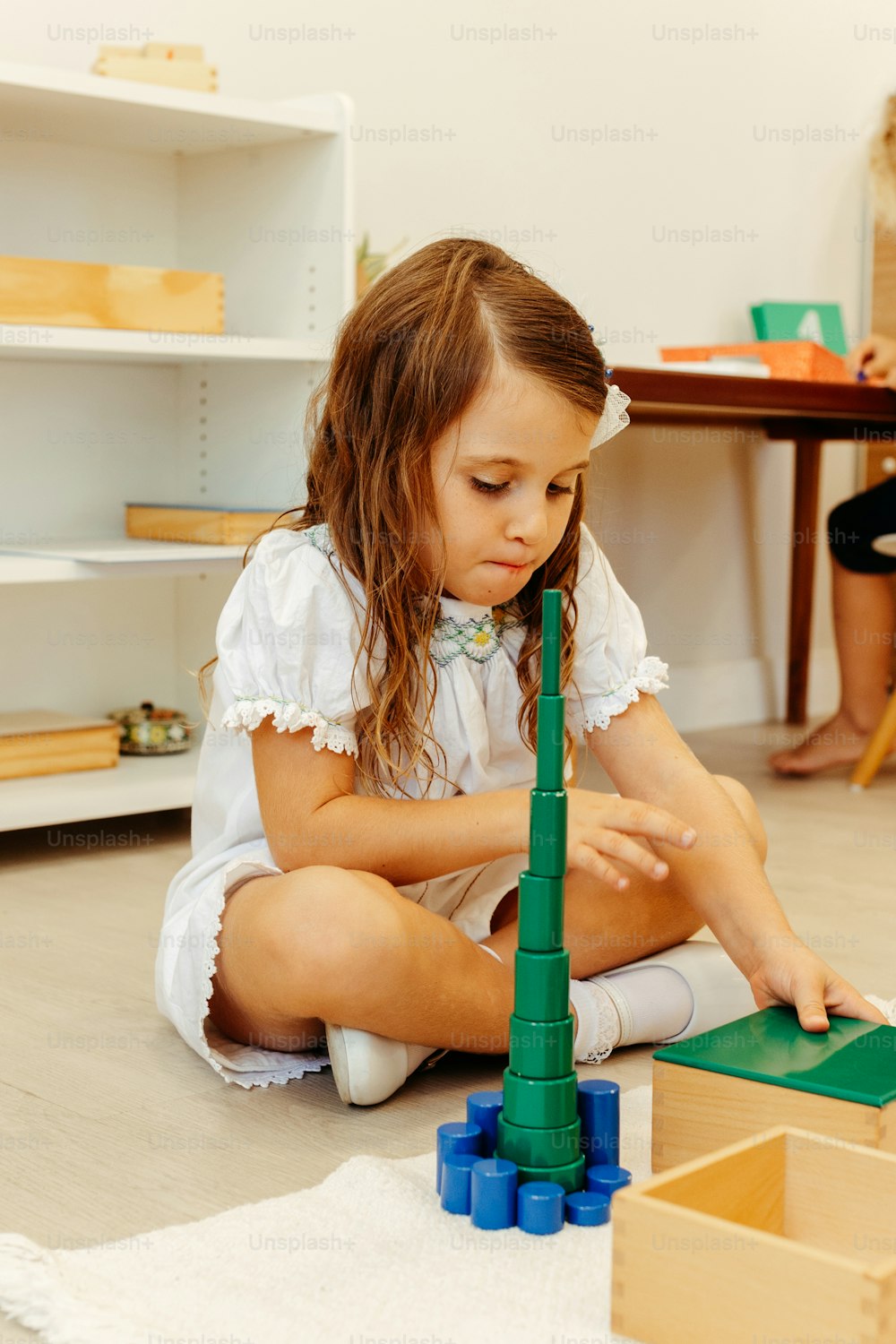 a little girl playing with a green tower