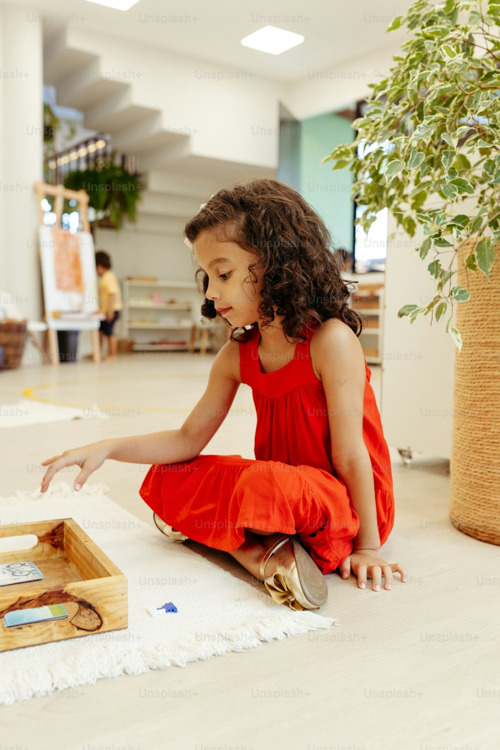 a little girl sitting on the floor playing with a wooden box