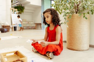 a little girl sitting on the floor playing with a video game