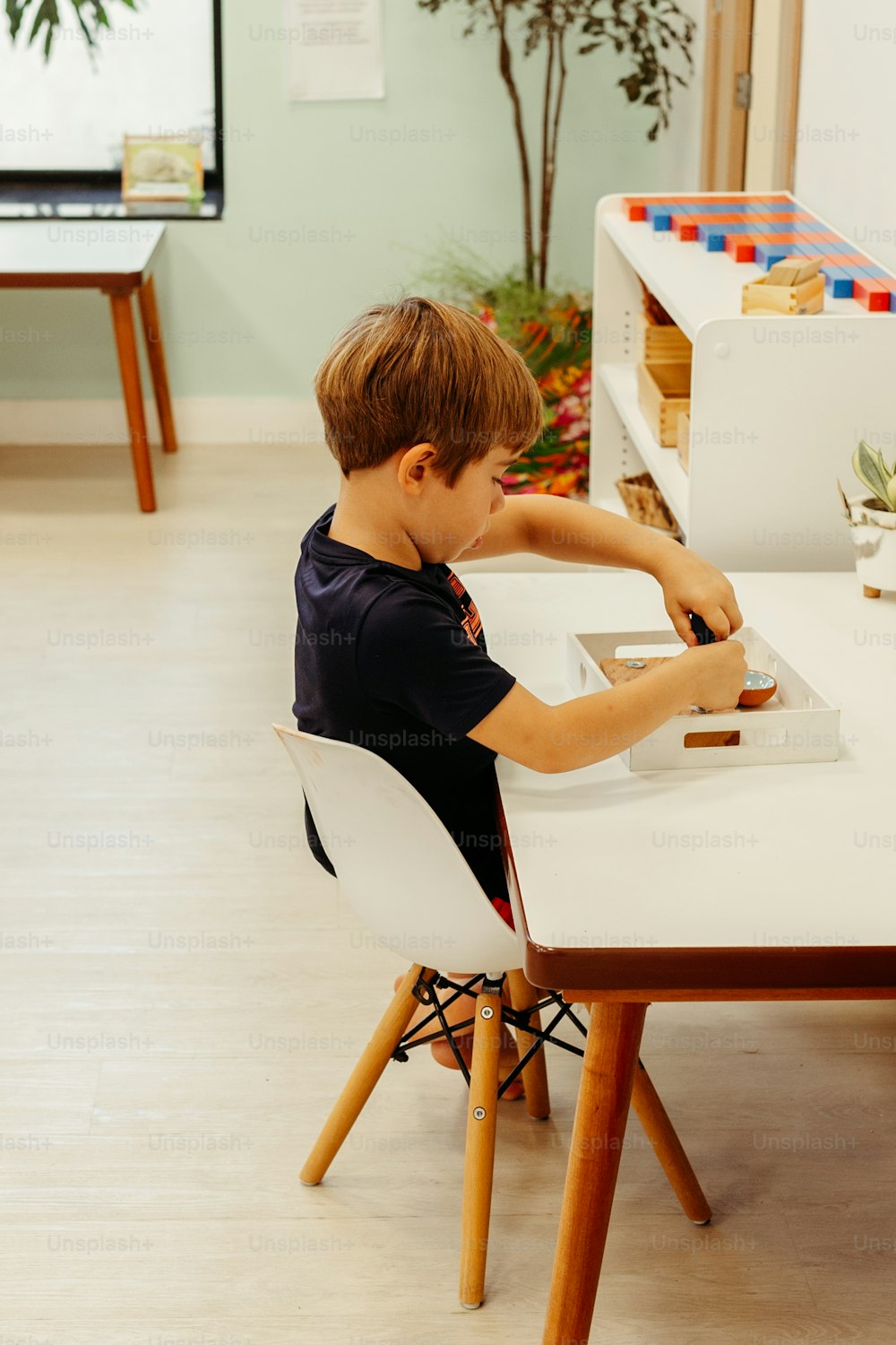 um menino sentado em uma mesa branca com uma cadeira branca