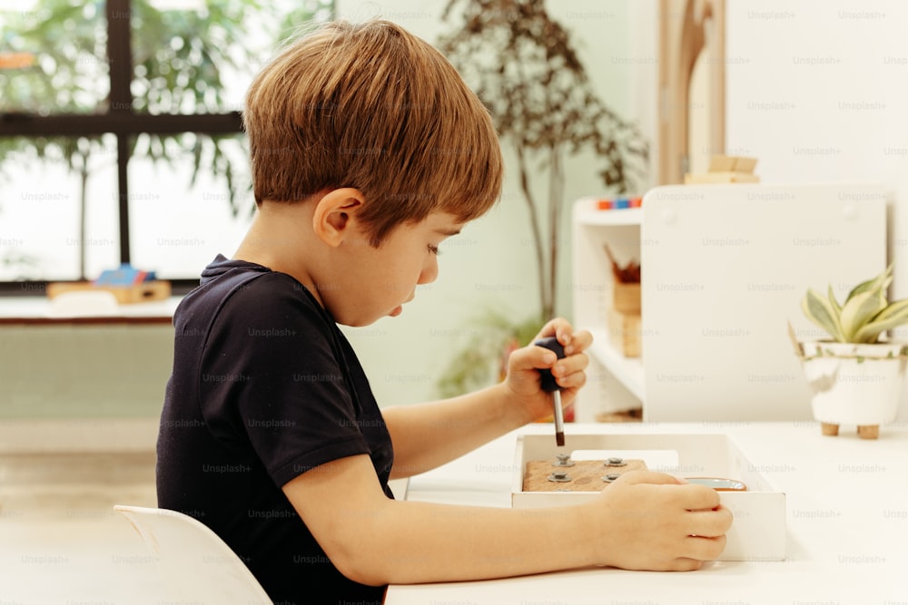 Un niño sentado en una mesa con lápiz y papel