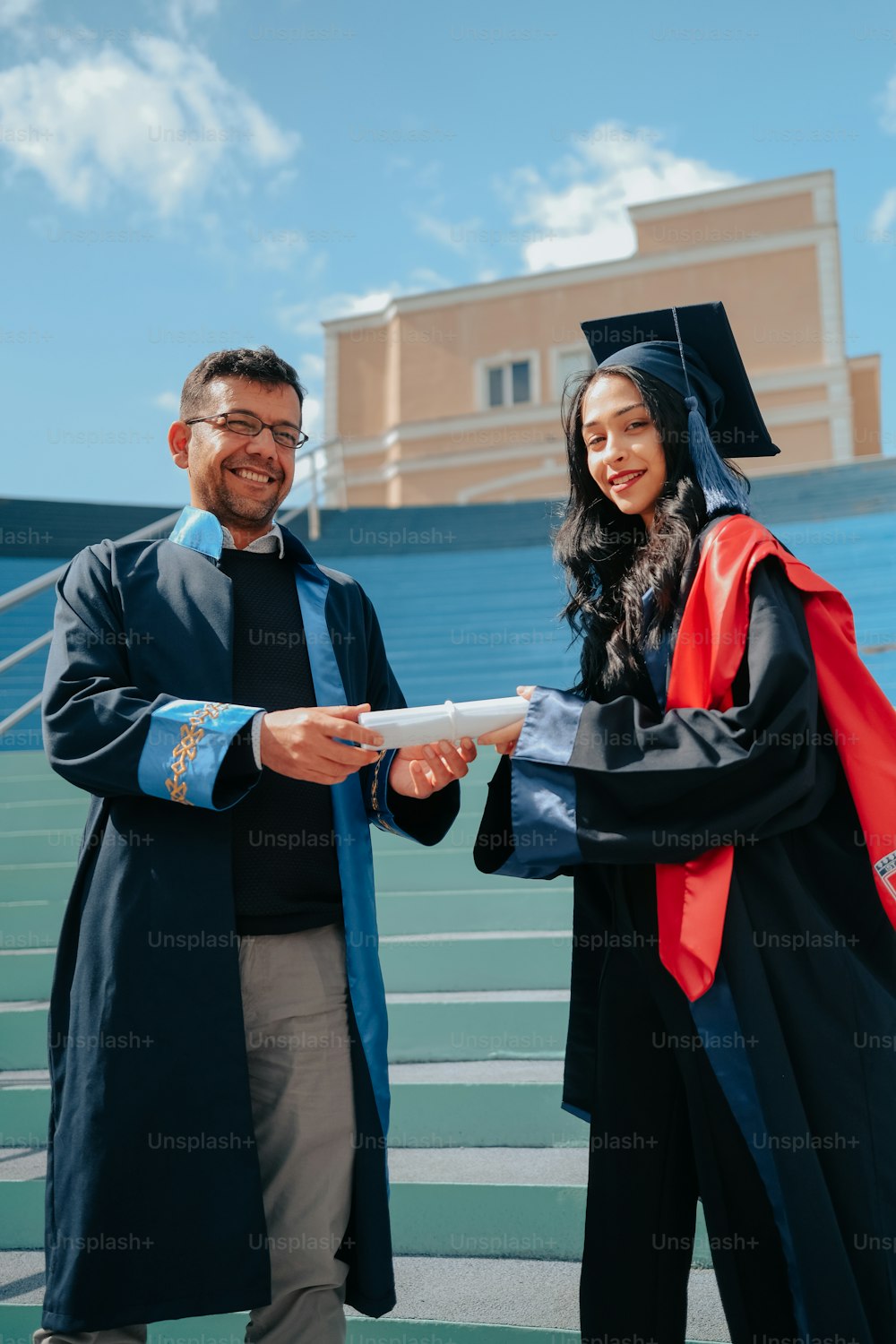 男性と握手する卒業式のガウンを着た女性