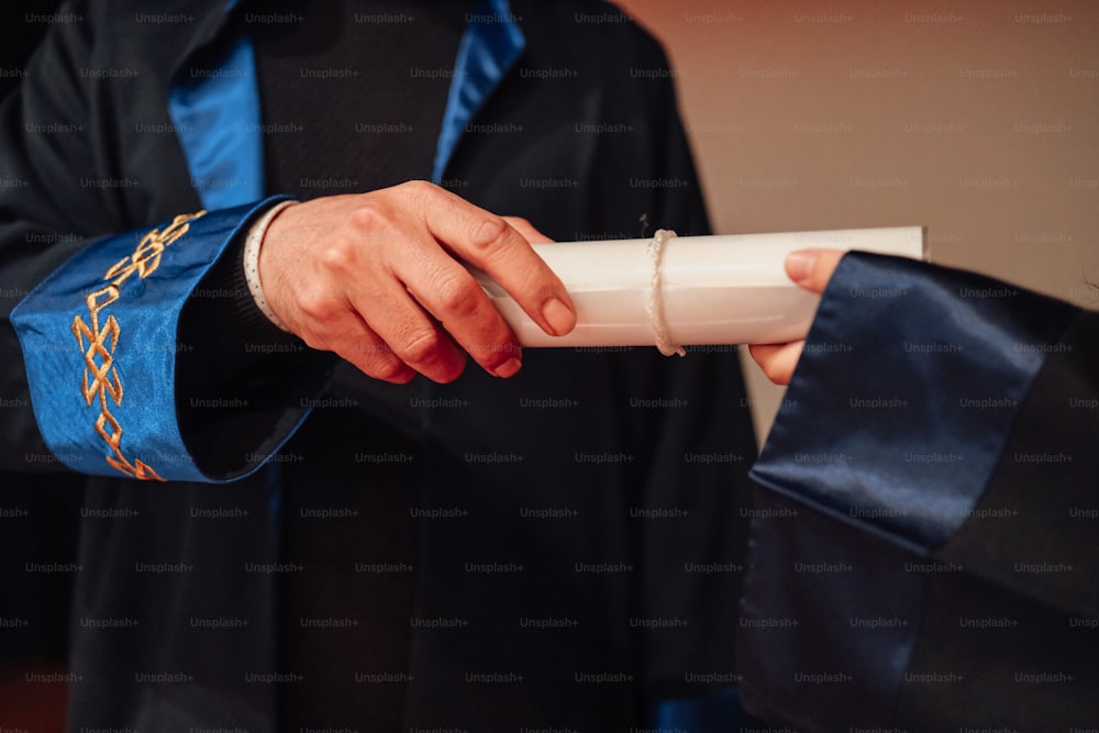 una persona in un abito da laurea in possesso di un diploma