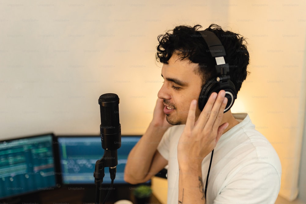 um homem usando fones de ouvido enquanto estava sentado em frente a um microfone