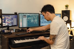a man sitting at a keyboard in front of two monitors