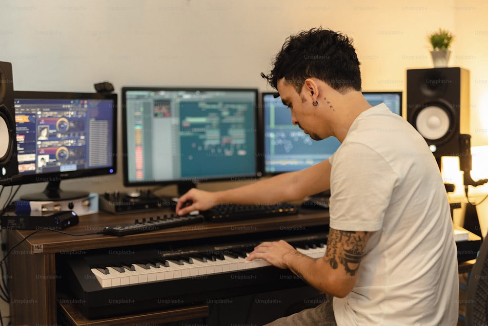 Un hombre sentado frente a un teclado frente a dos monitores