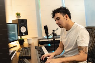 a man sitting at a keyboard in front of a microphone