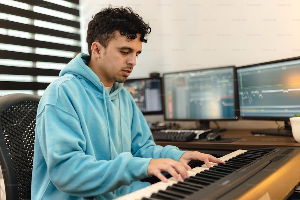 a man sitting at a keyboard in front of two monitors